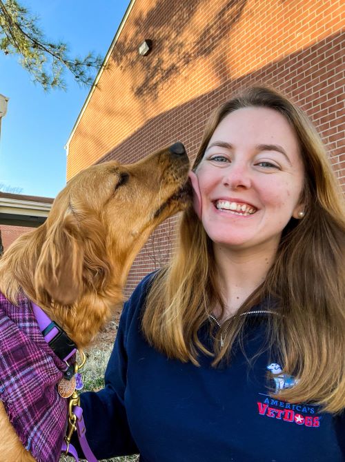 Cate Law dog trainer in Virginia Beach with her Golden Addy licking her face