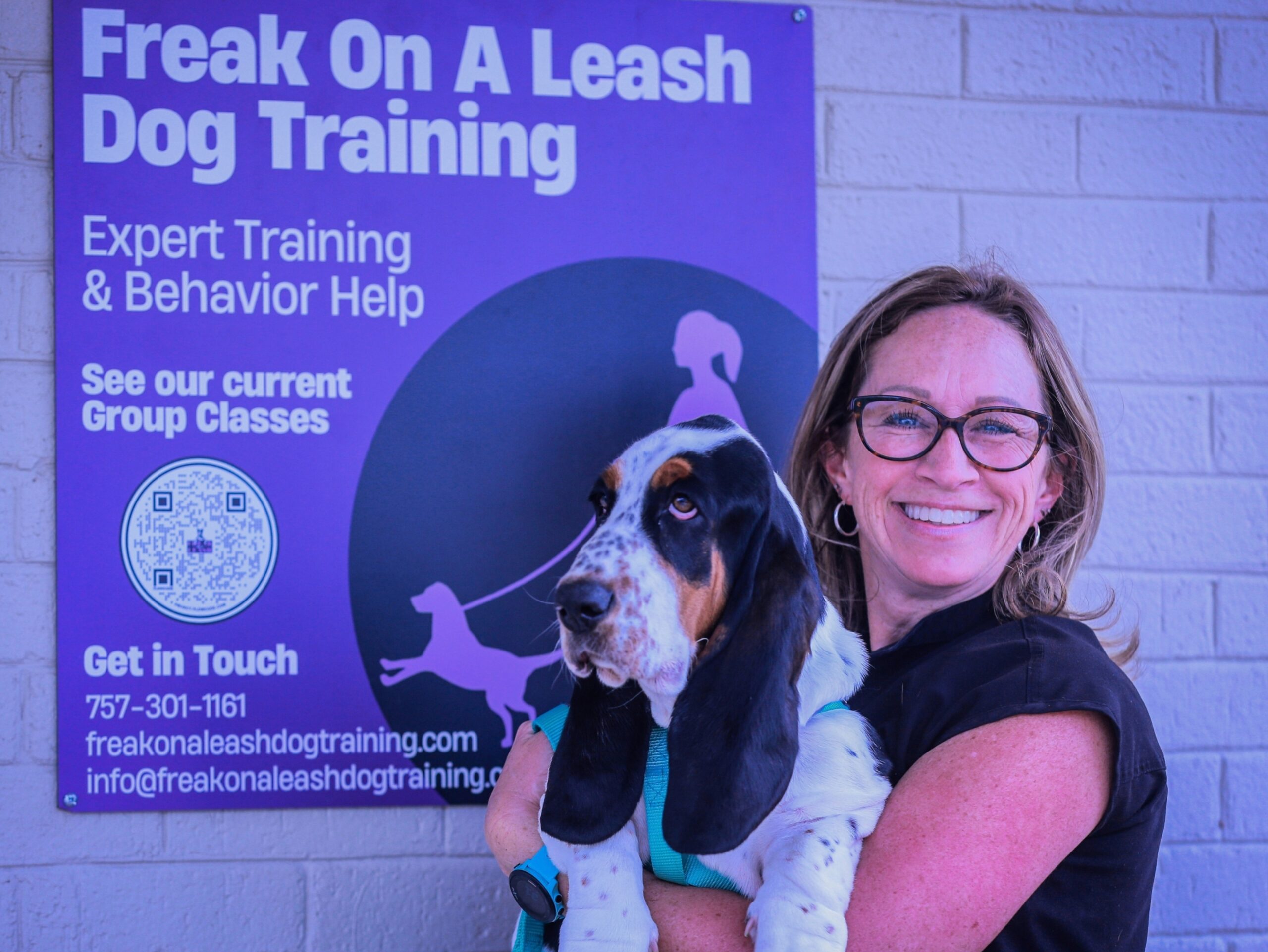 Doodle puppy in male owners arms in front of Freak On A Leash facility in Chesapeake