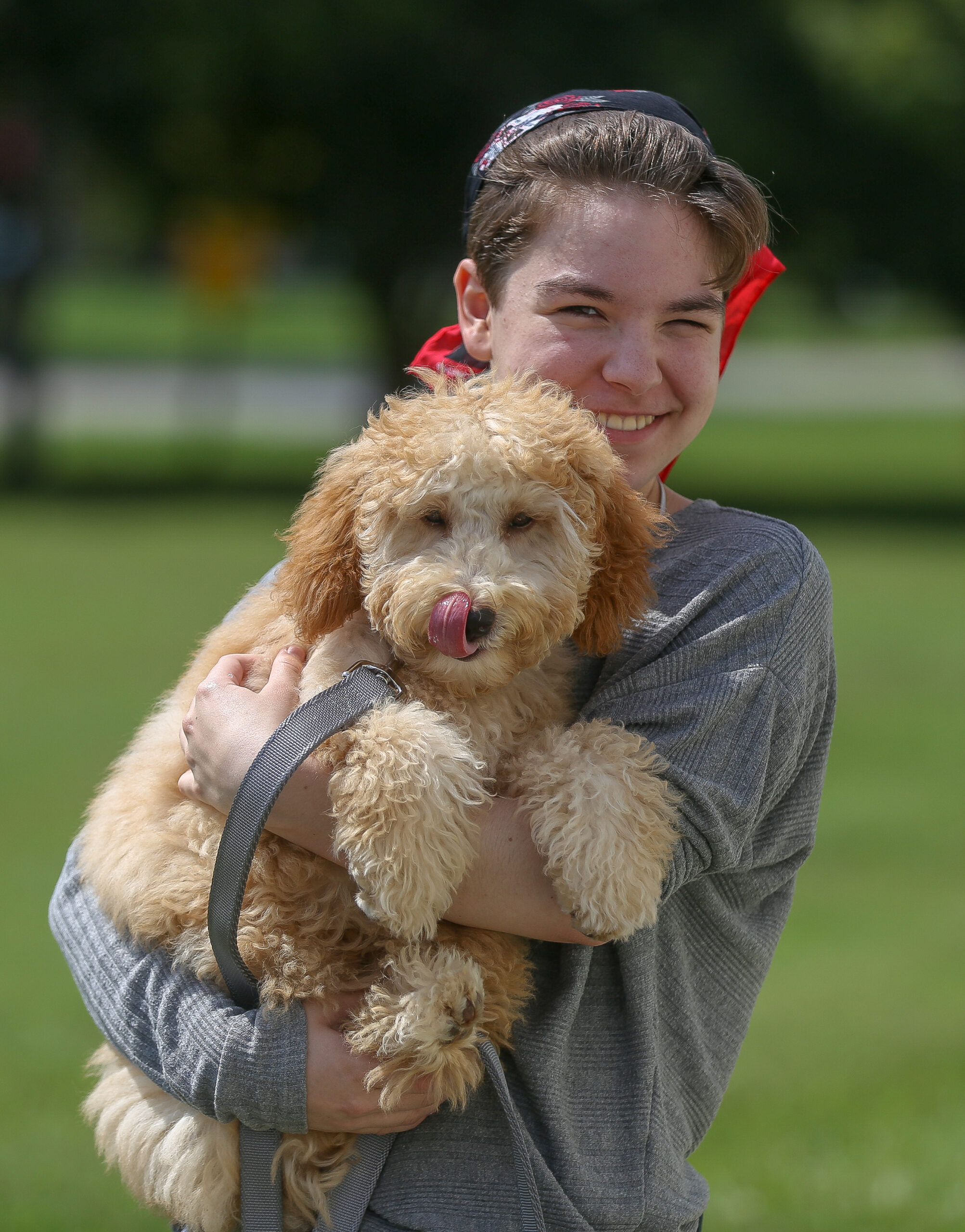 Doodle puppy in male owners arms in front of Freak On A Leash facility in Chesapeake